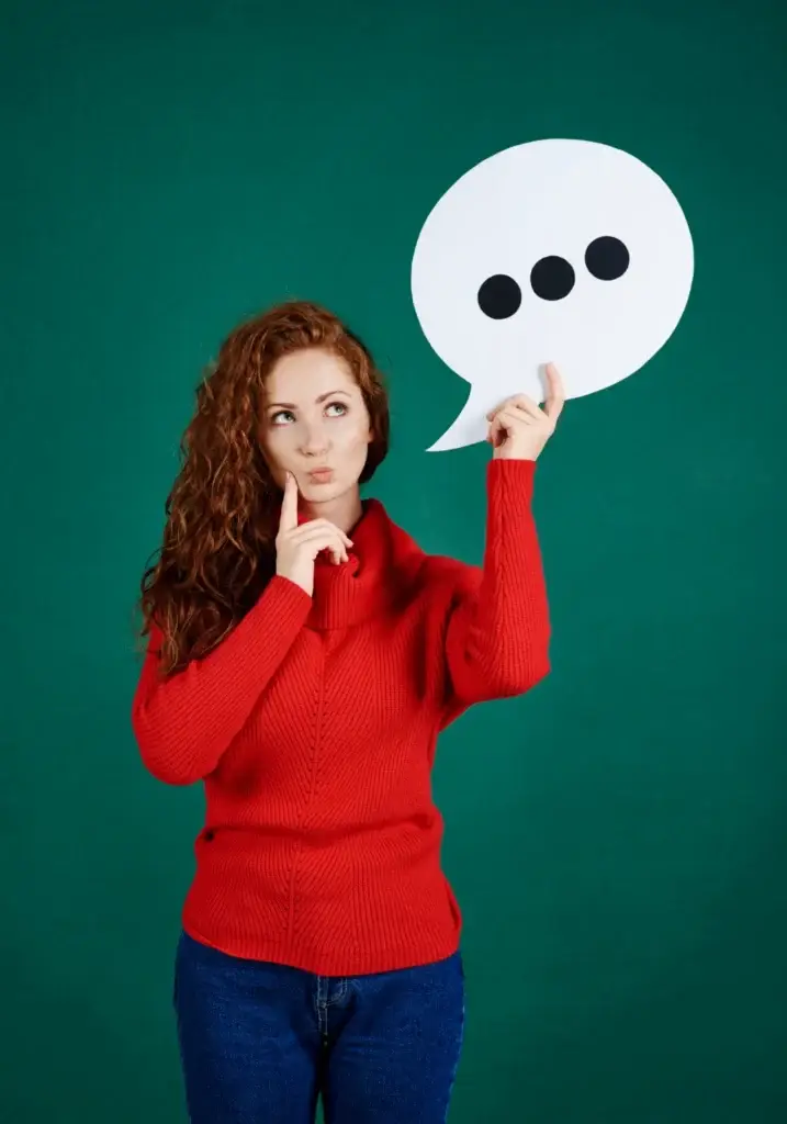 une femme rousse, cheveu long,avec un pulle rouge et jean bleu qui se pose des questions sur les services que proposent Evstel call center ne France.
